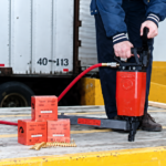Worker using a Pneutek pneumatic fastening tool on truck and trailer flooring.