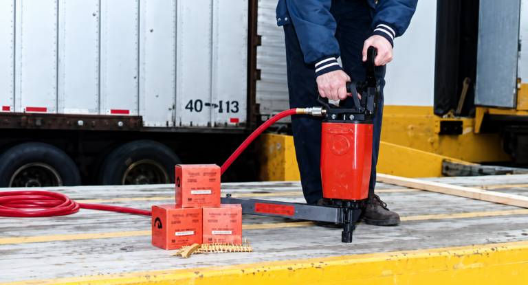Worker using a Pneutek pneumatic fastening tool on truck and trailer flooring.
